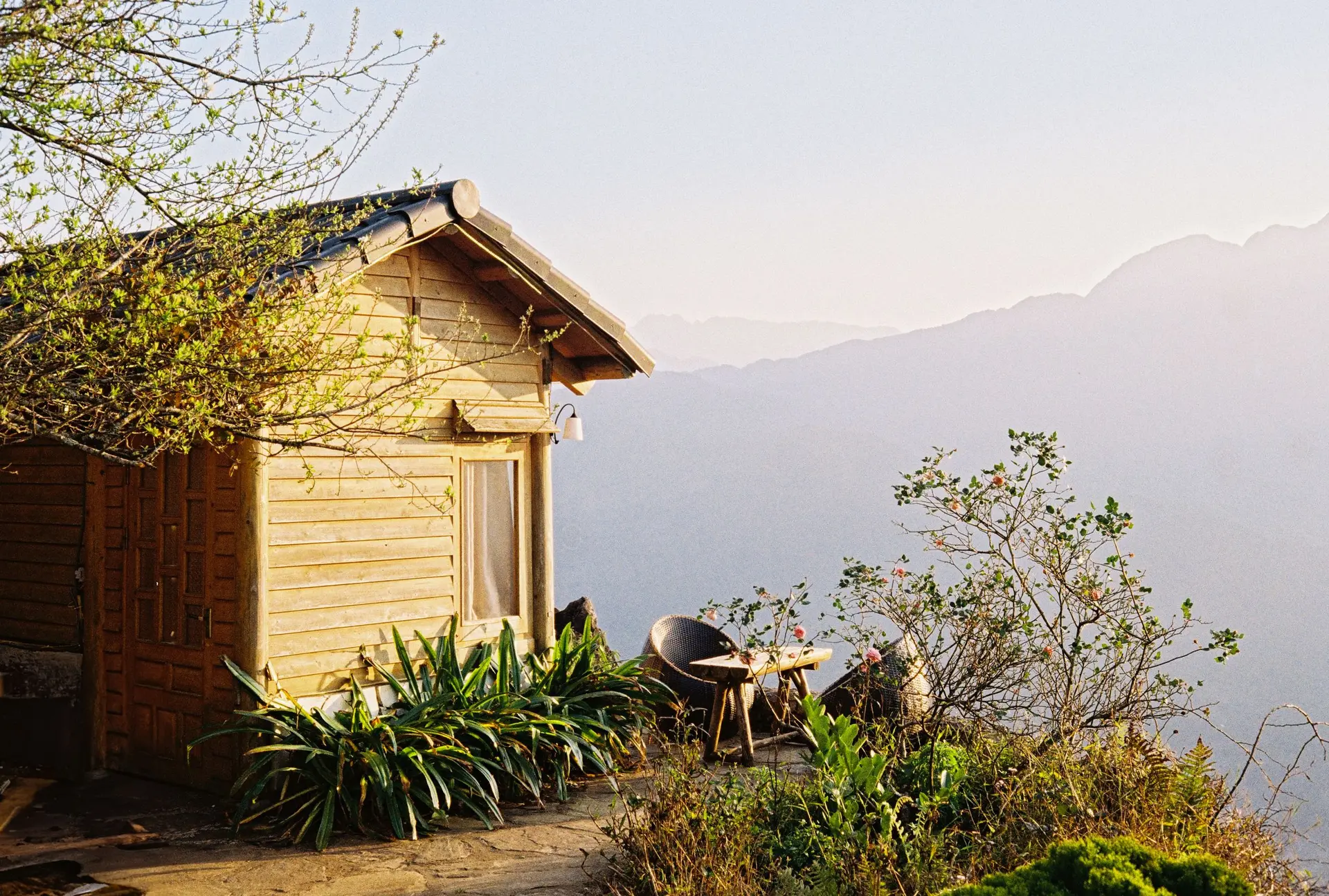 Small wooden cabin with a patio above a misty valley