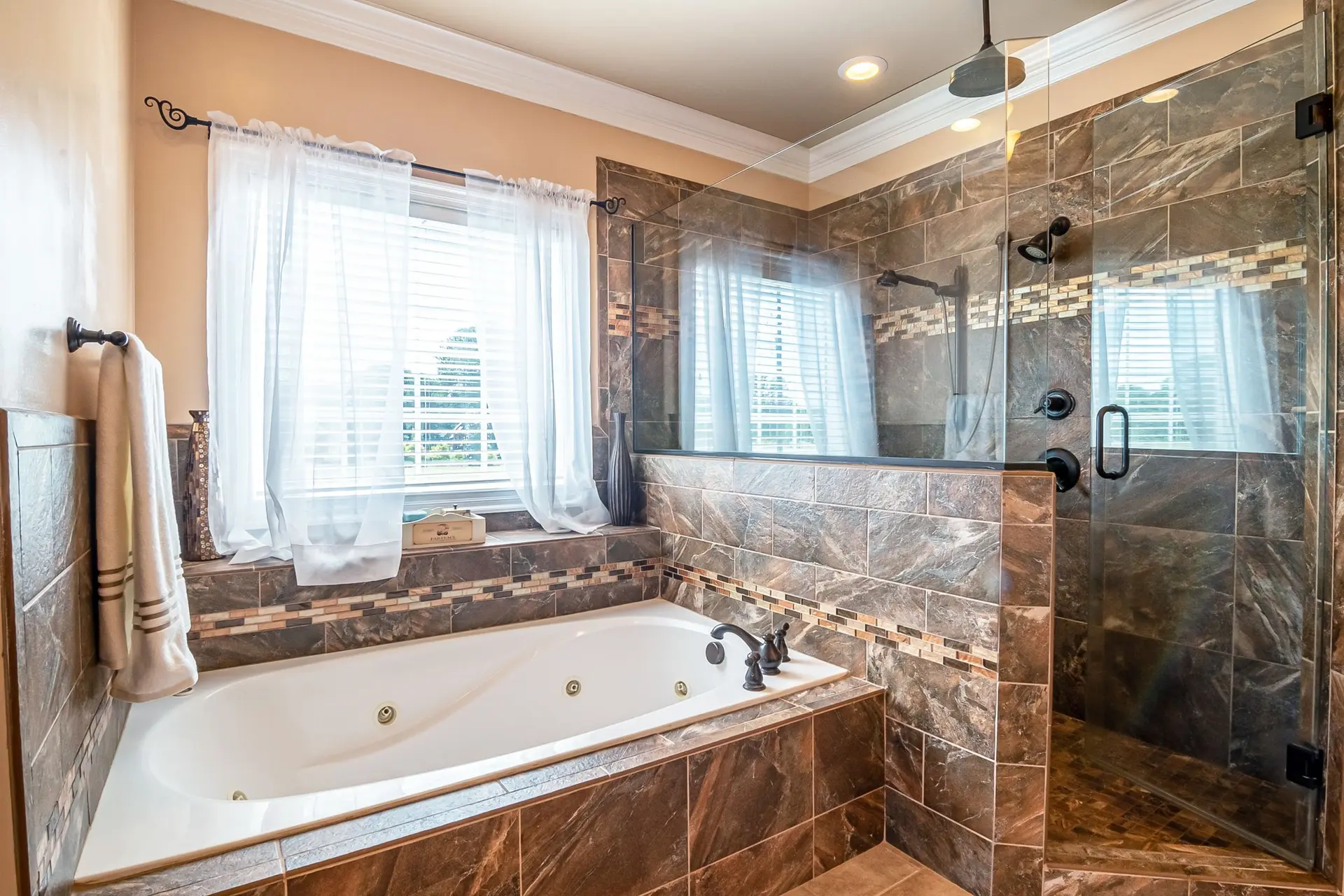 Bathroom with a soaking tub and a glass walk-in shower in marble tile