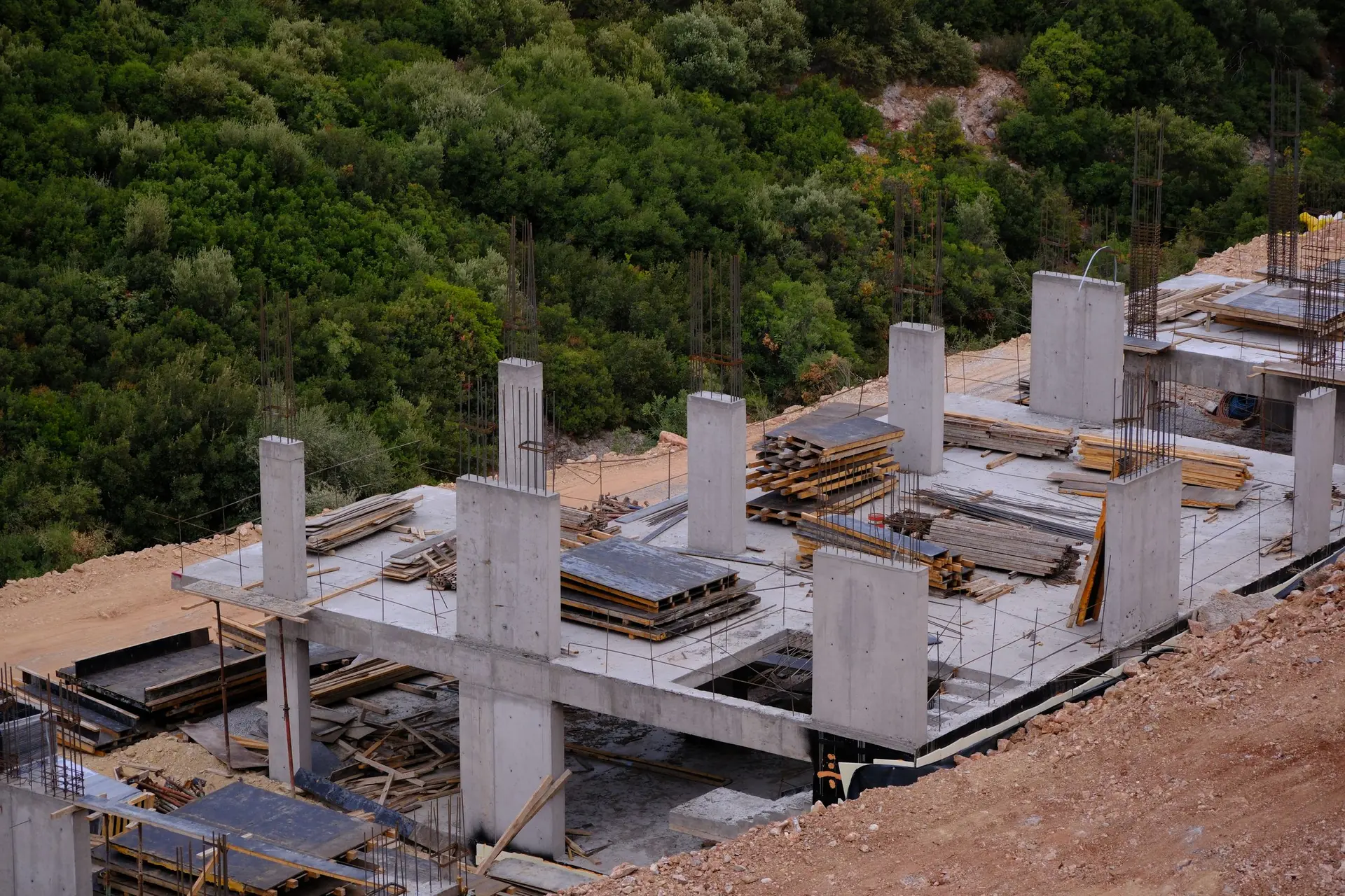 Concrete columns and slab of a building under construction among trees