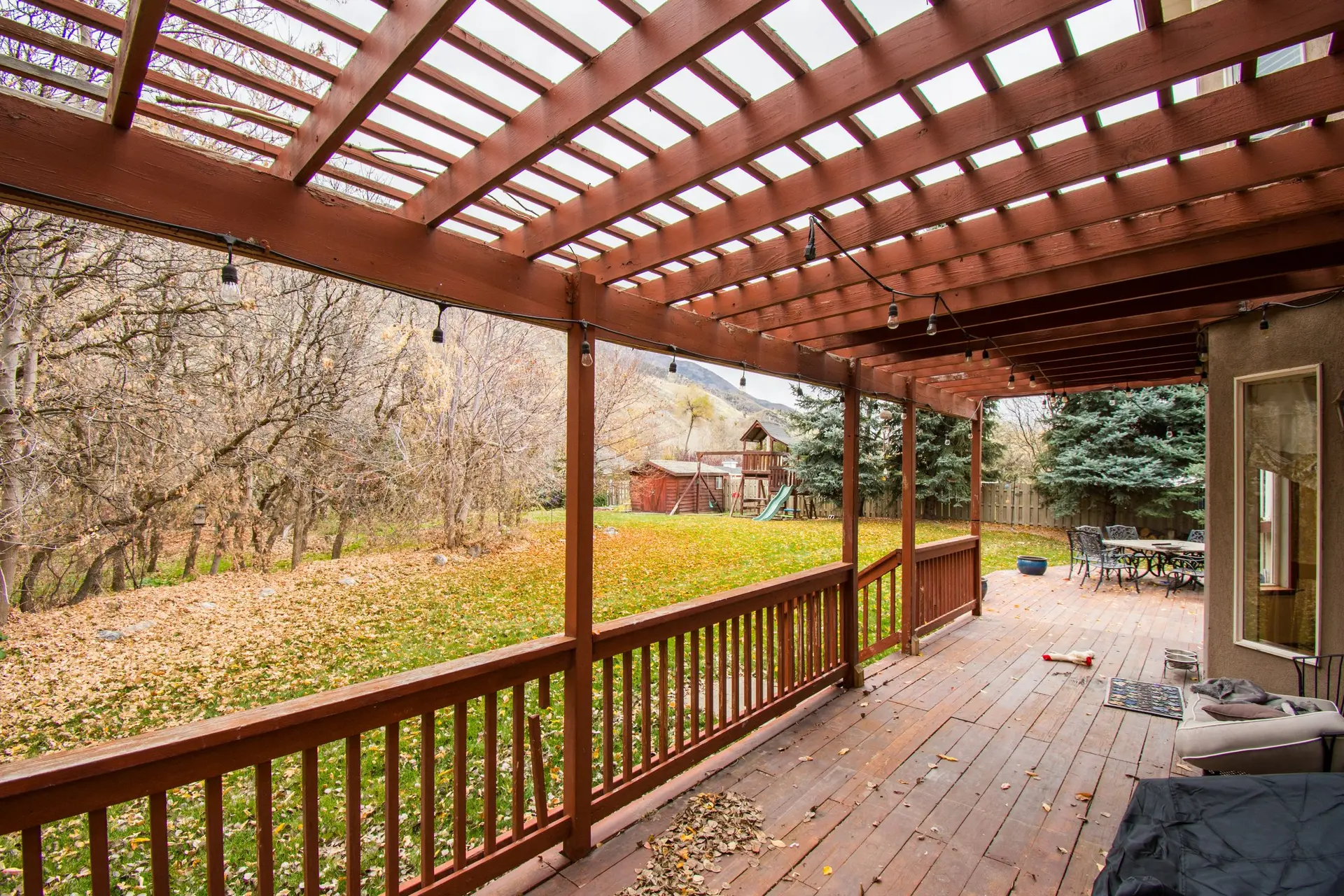 Covered wood deck with a pergola roof looking over a wooded yard