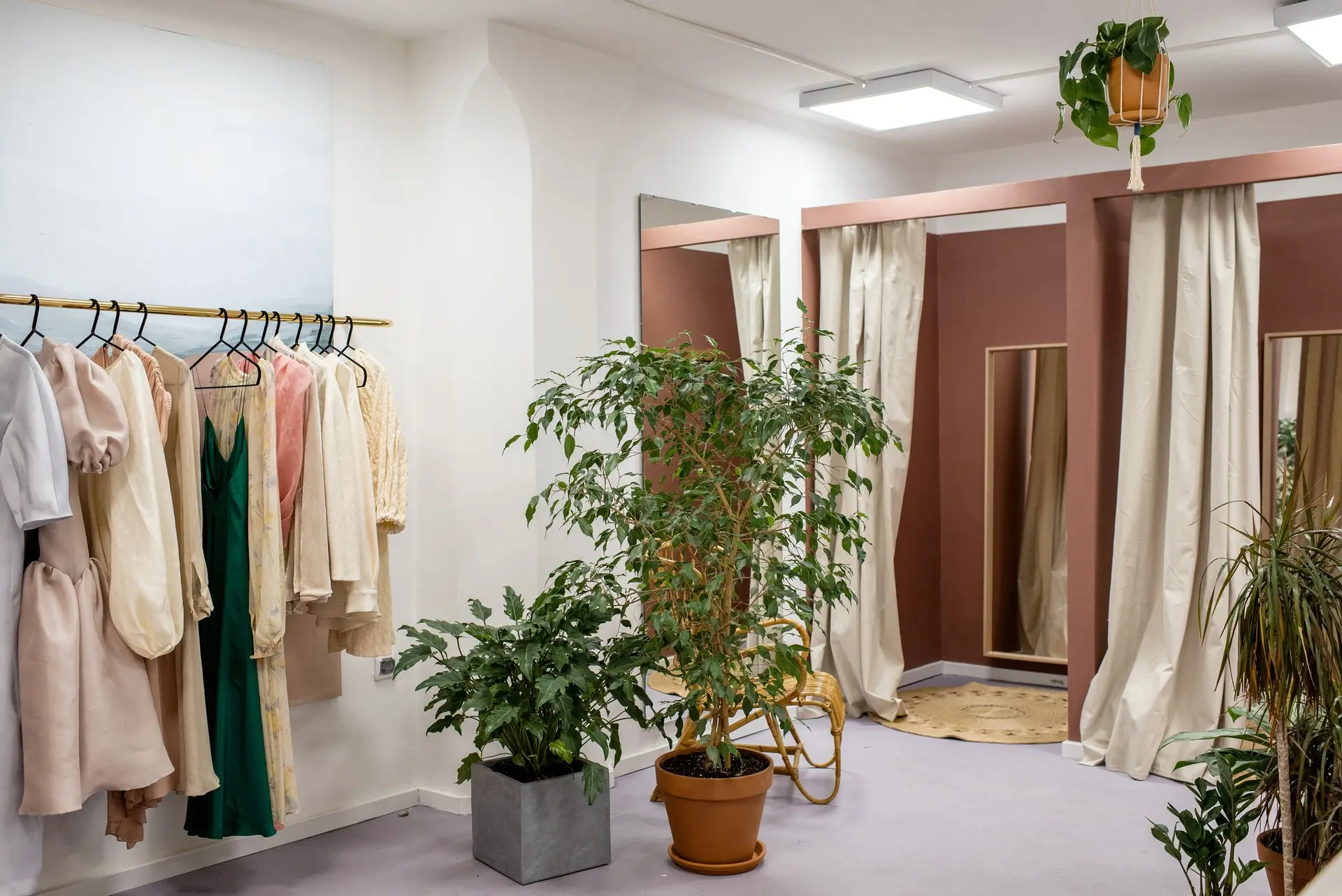 Boutique with garments on a rail, plants and fitting room curtains