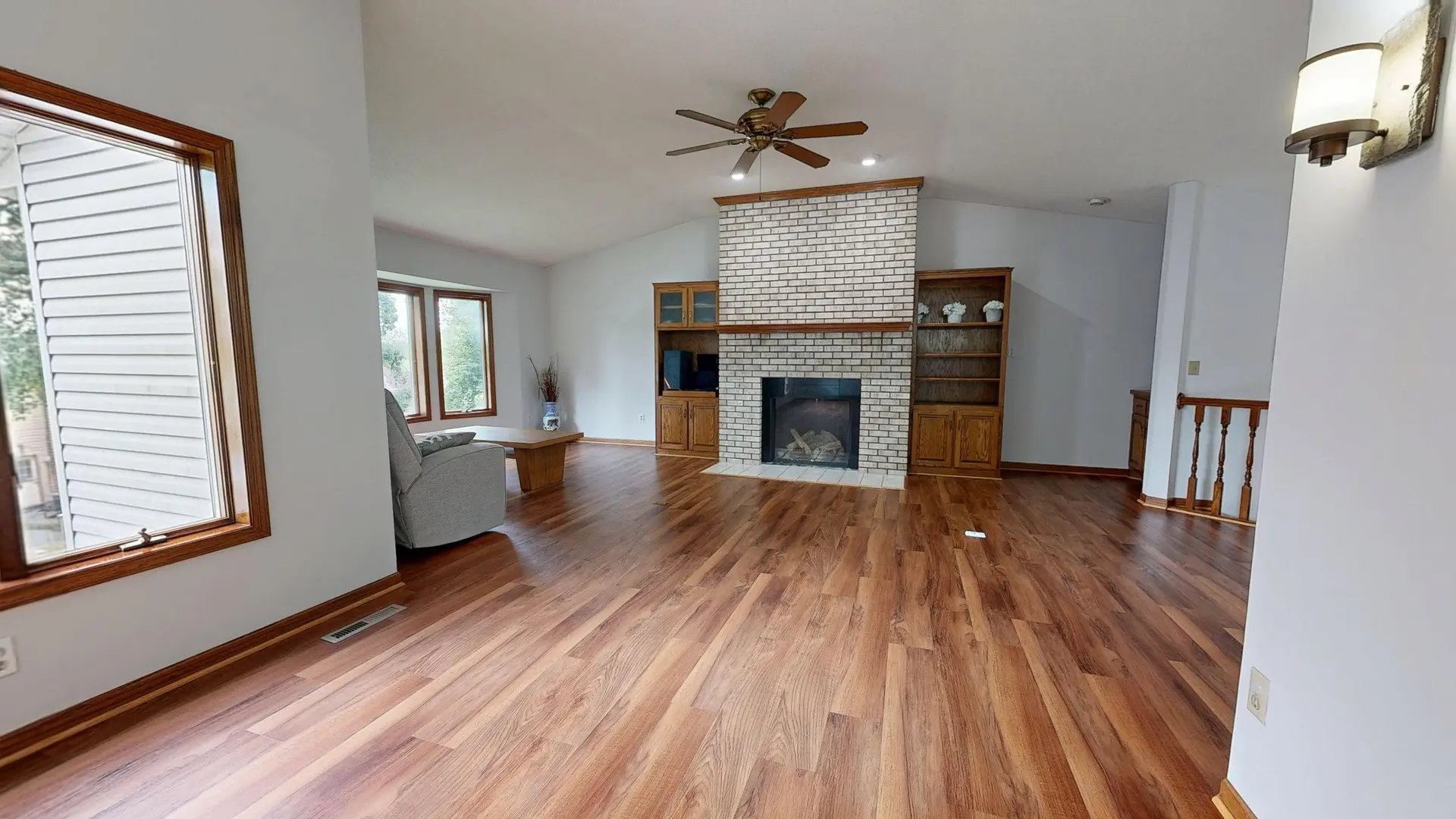 Open living room with wood floors and a brick fireplace